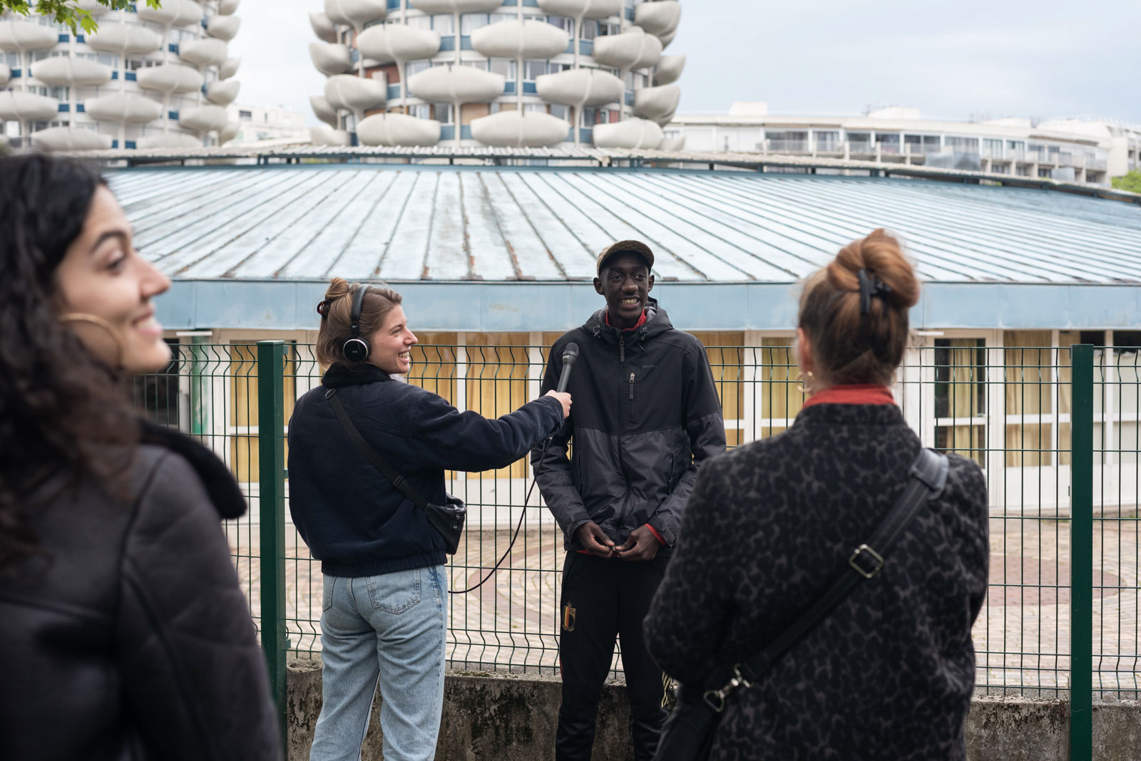 A local guide presents the architectural details of the school on the microphone to record a podcast for the tour of the Palais a Creteil district in 2023.Un habitant guide presente les particularites architecturales de l ecole au micro pour enregistrer un podcast pour le tour du quartier du Palais a Creteil en 2023.