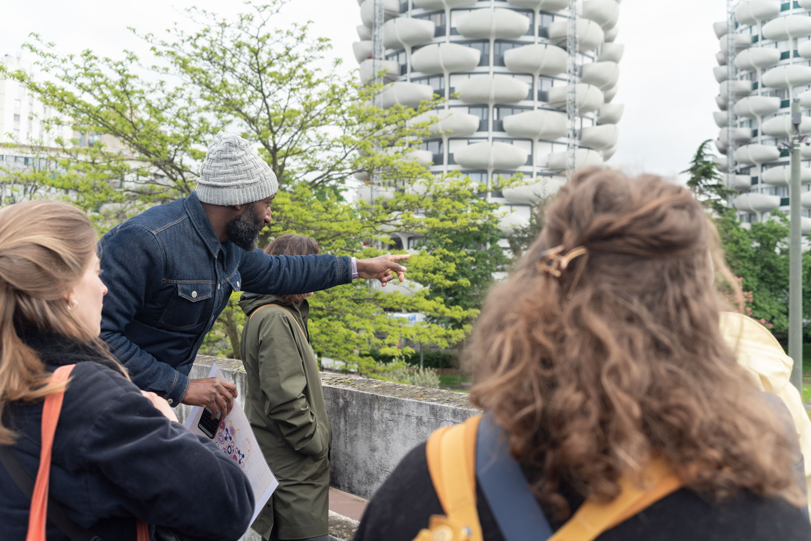 A local guide presents to visitors the architectural particularities the cabbage shaped buildings in the Palais district in Creteil in 2023.Un habitant guide presente aux visiteurs les particularites architecturales des immeubleus en forme de choux dans le quartier du Palais a Creteil en 2023.